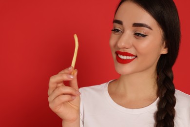 Photo of Beautiful young woman with French fries on red background