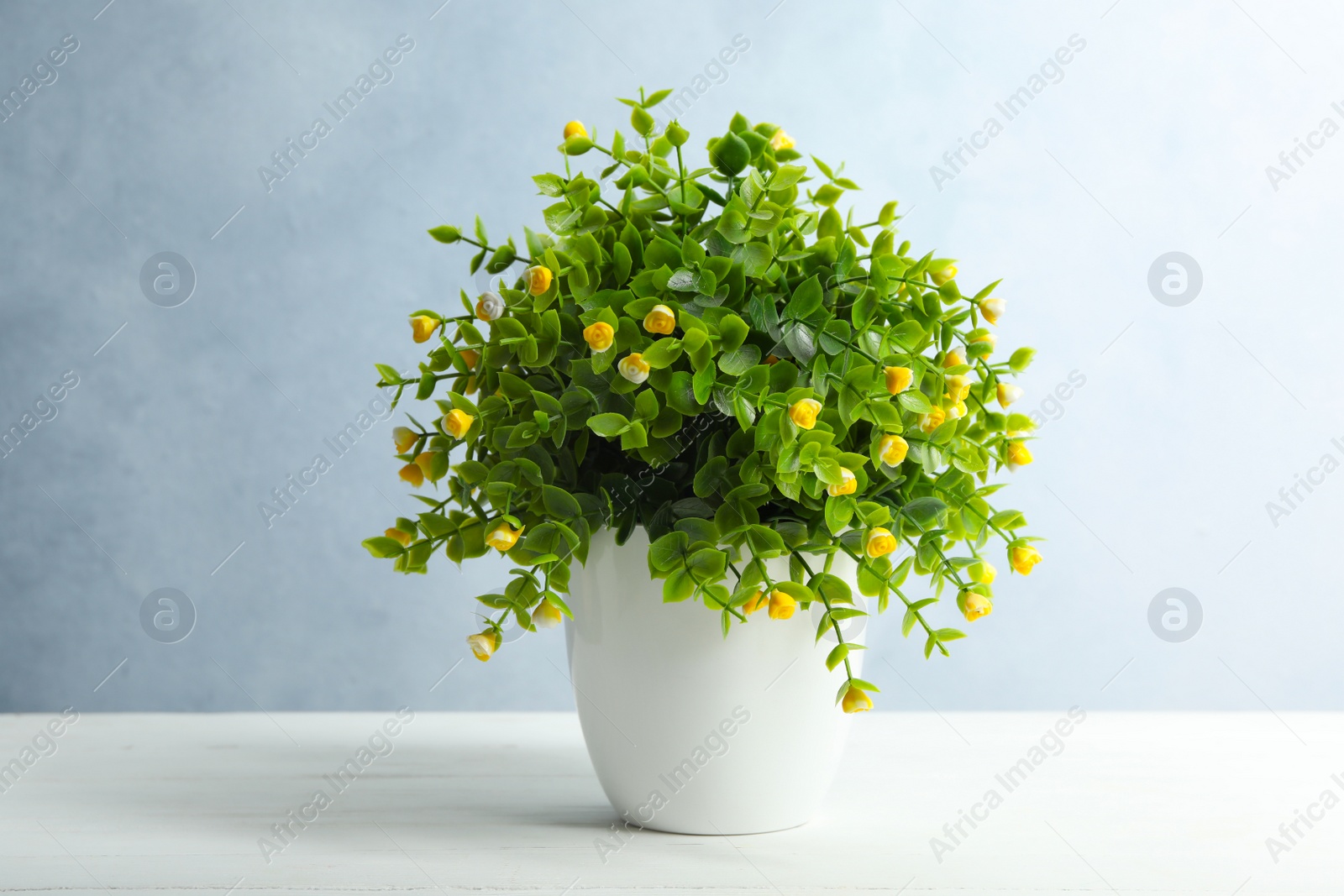 Photo of Artificial plant in flower pot on white wooden table