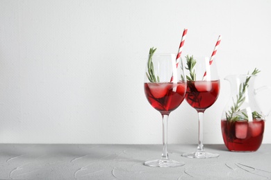 Photo of Glasses of fresh cranberry cocktail with rosemary and space for text on light background