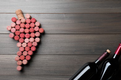 Photo of Grape made of wine corks and bottles on wooden table, flat lay. Space for text