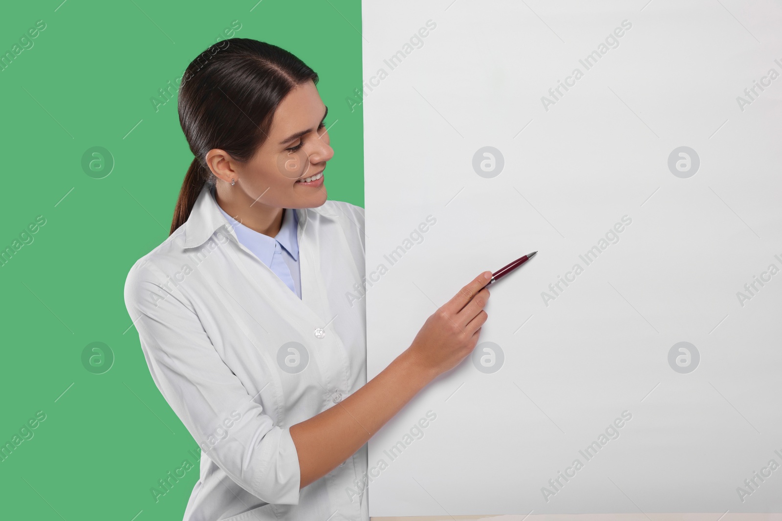 Photo of Ophthalmologist pointing at blank banner on green background, space for text