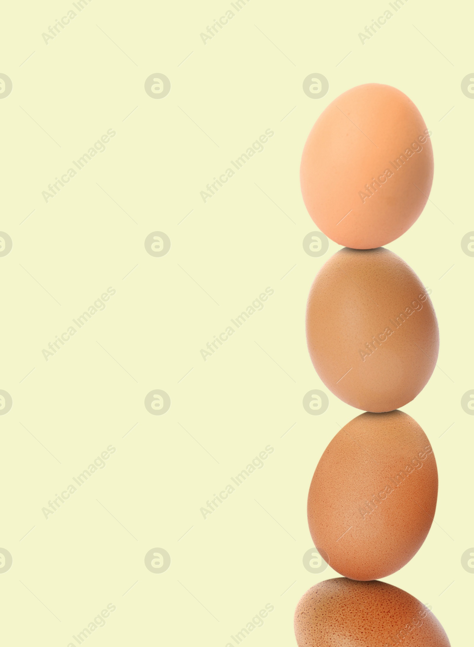 Image of Stacked fresh chicken eggs against light beige background. Space for text