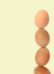 Stacked fresh chicken eggs against light beige background. Space for text