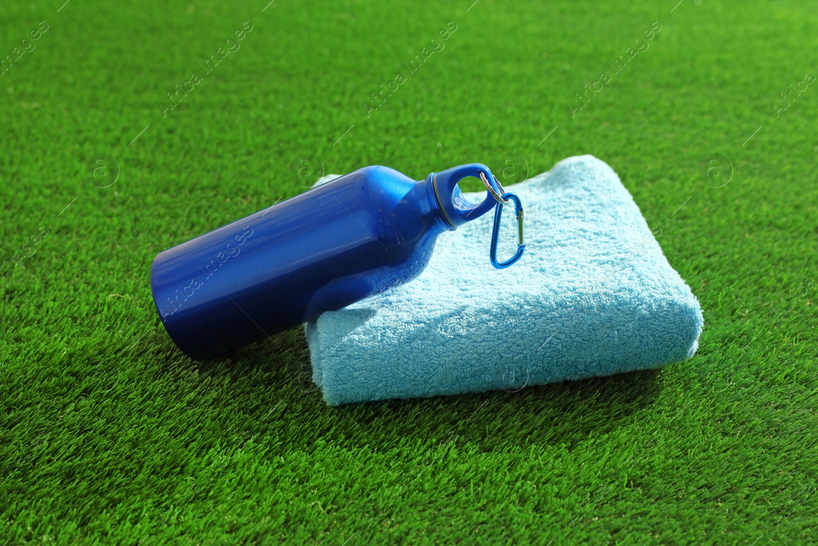 Photo of Bottle of water and towel on artificial grass. Fitness equipment