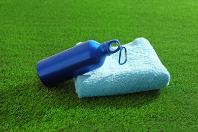 Photo of Bottle of water and towel on artificial grass. Fitness equipment