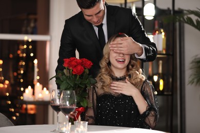 Man presenting roses to his beloved woman in restaurant at Valentine's day dinner