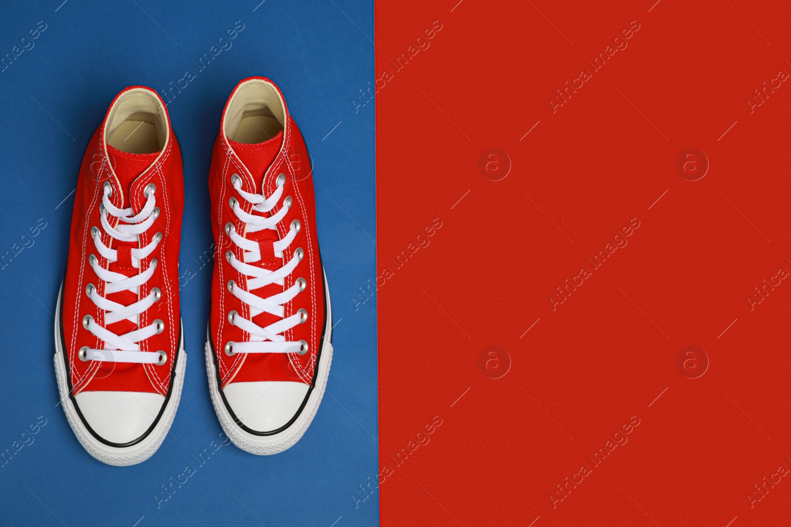 Photo of Pair of new stylish red sneakers on colorful background, flat lay. Space for text