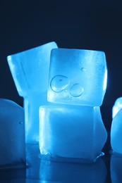 Photo of Crystal clear ice cubes on dark background, closeup. Color tone effect