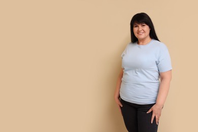 Photo of Beautiful overweight mature woman with charming smile on beige background. Space for text