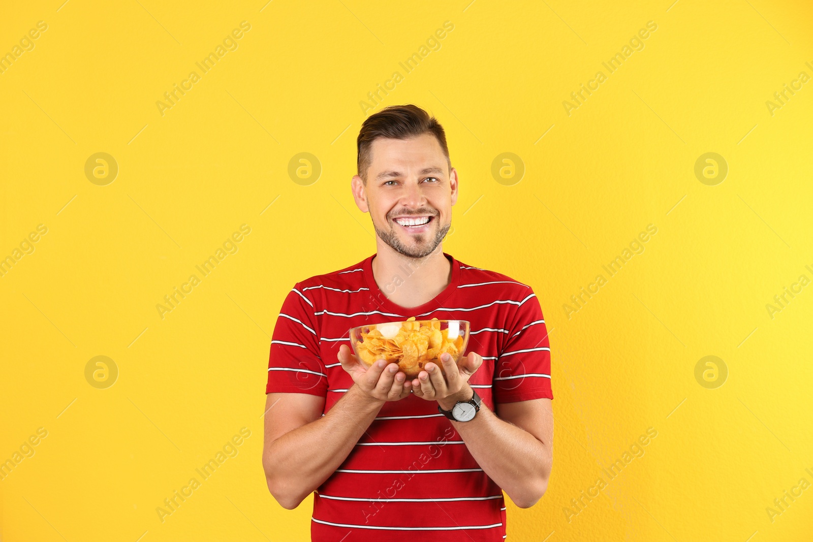 Photo of Man with bowl of potato chips on color background