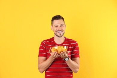 Photo of Man with bowl of potato chips on color background