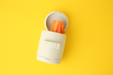 Dispenser with dog waste bags on yellow background, top view