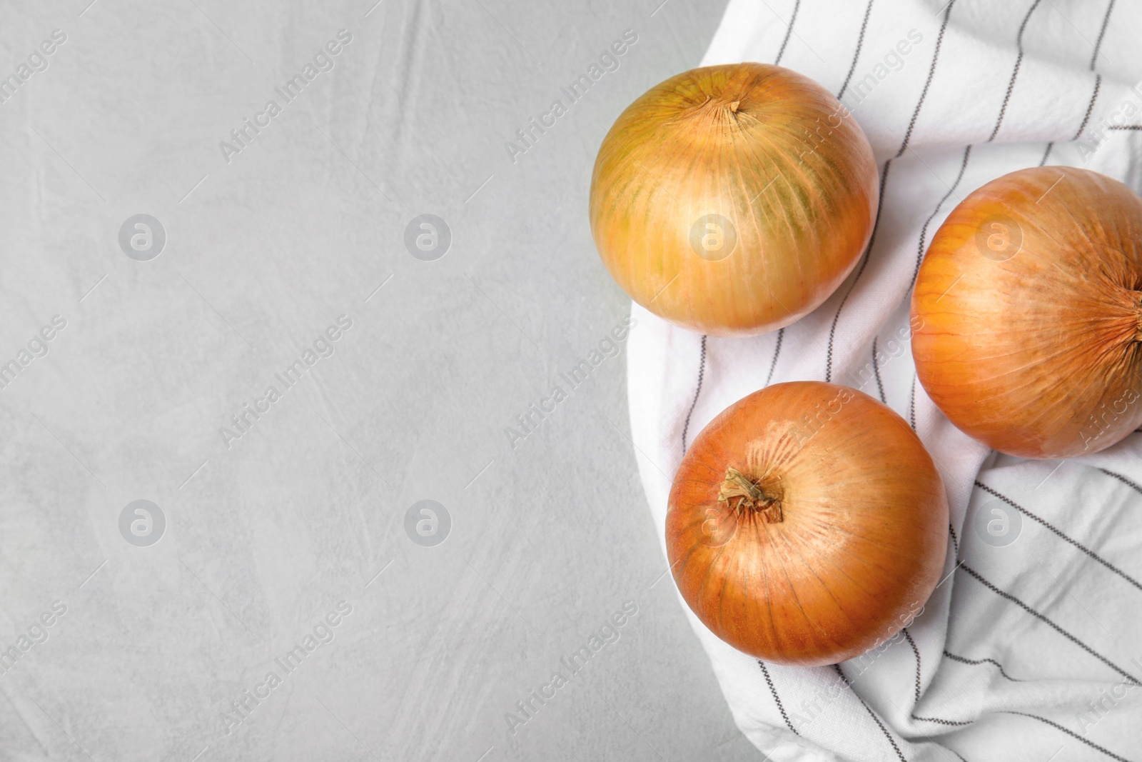 Photo of Fabric with ripe onions on grey table, flat lay. Space for text