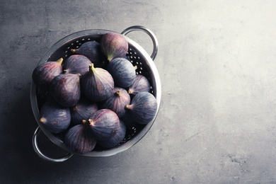 Photo of Colander with fresh ripe figs on gray background, top view. Space for text