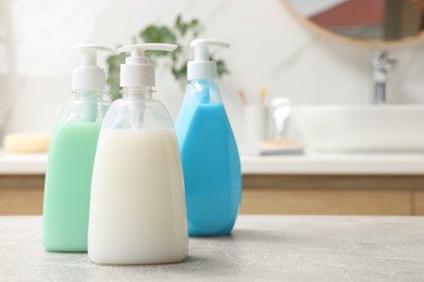 Photo of Dispensers of liquid soap on light grey table in bathroom, space for text