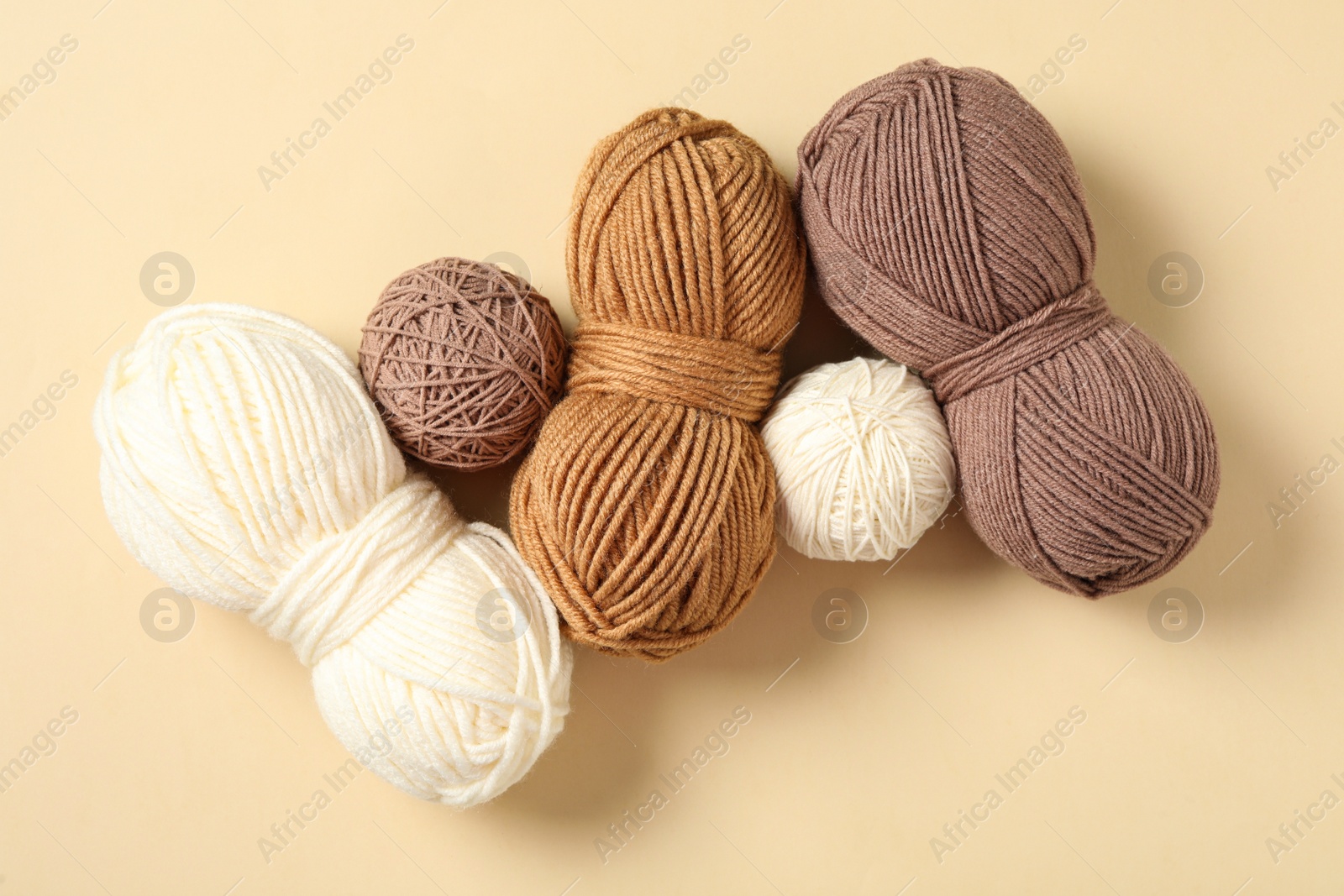 Photo of Colorful woolen yarns on beige background, flat lay