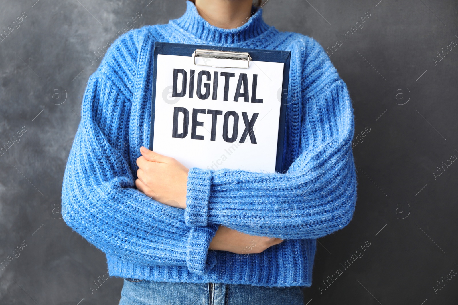 Photo of Woman holding clipboard with phrase DIGITAL DETOX on grey background, closeup