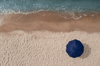 Image of Beach umbrella on sandy coast near sea, top view