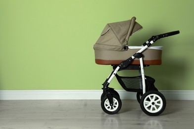 Baby carriage. Modern pram near light green wall, space for text