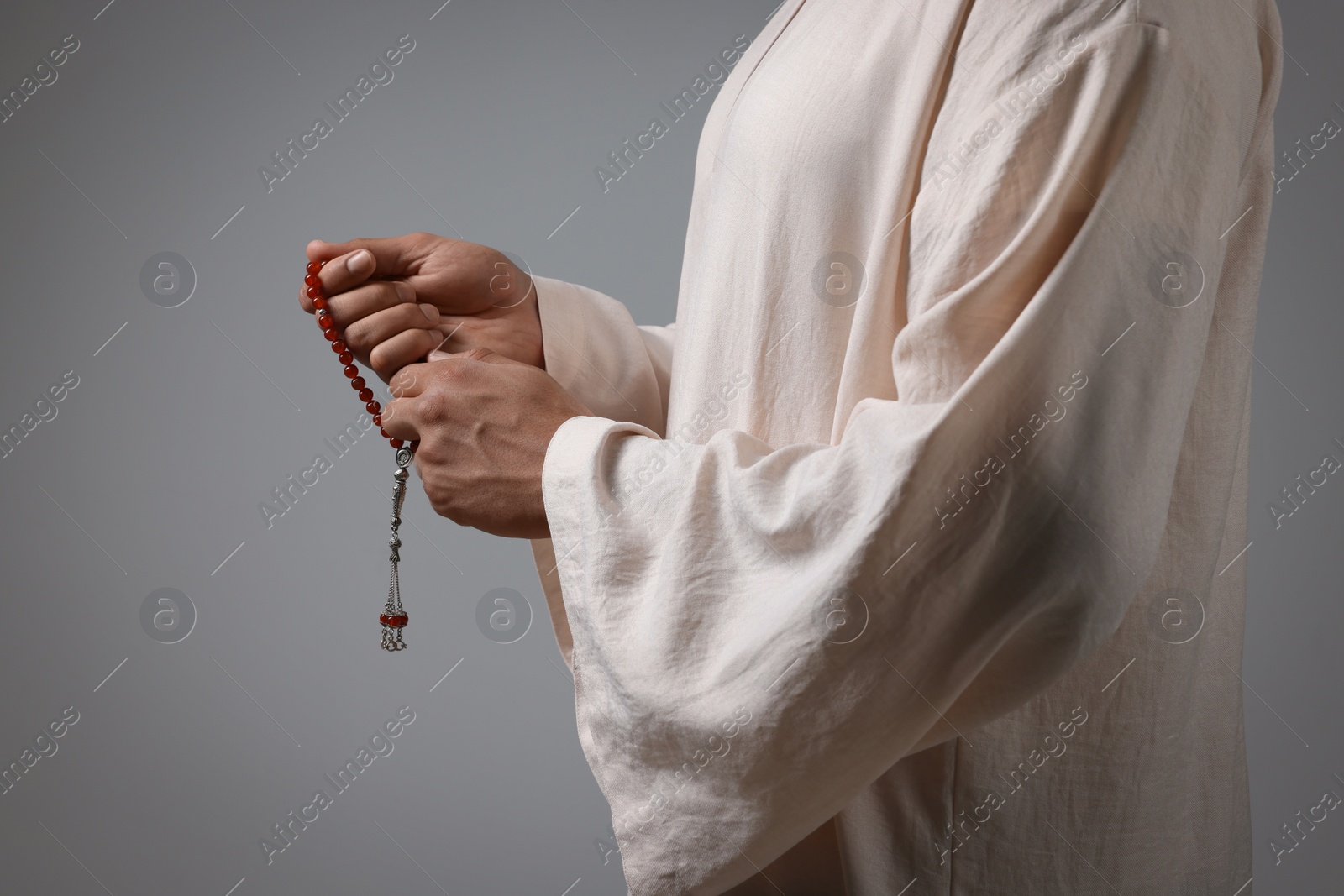 Photo of Muslim man with misbaha on light grey background, closeup