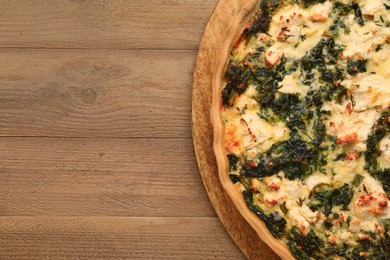 Delicious homemade spinach quiche on wooden table, top view. Space for text