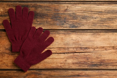 Stylish gloves on wooden background, flat lay. Space for text