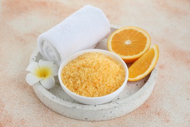 Photo of Sea salt, towel, plumeria flower and cut orange on beige textured table