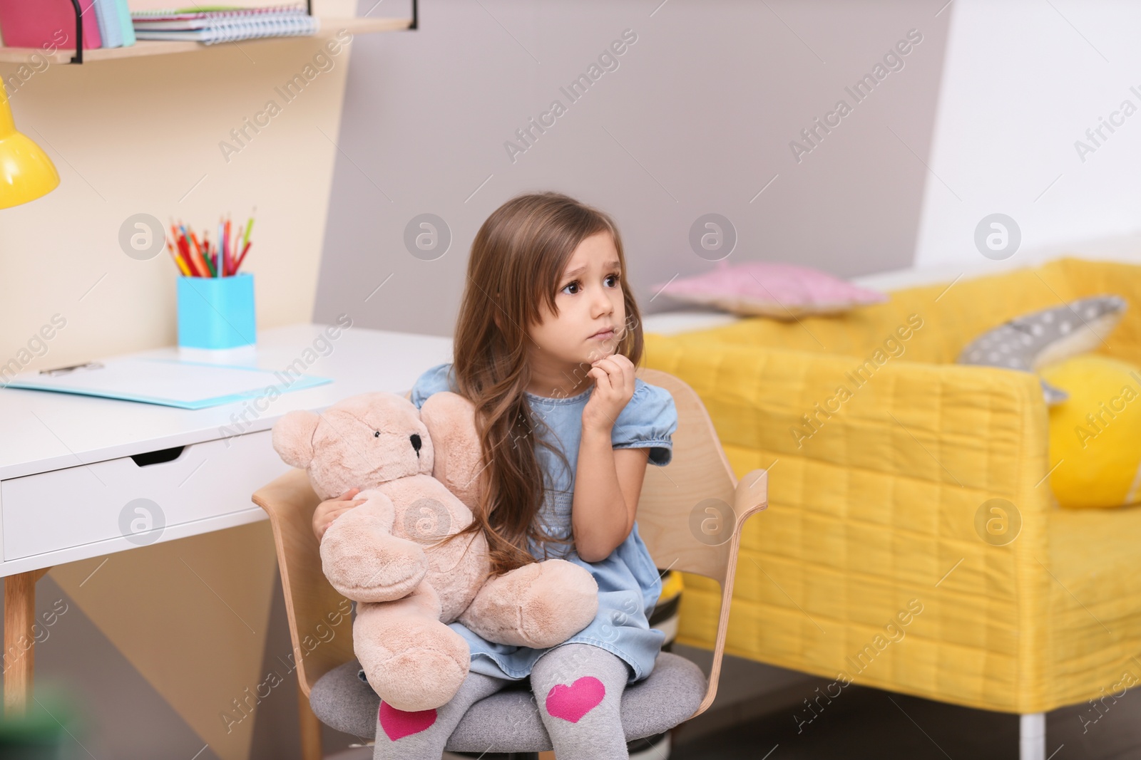 Photo of Cute little girl playing with toy bear at home