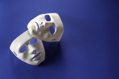 Photo of Theater arts. White masks on blue background, top view. Space for text