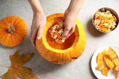 Photo of Woman making pumpkin head Jack lantern for Halloween at light table, top view