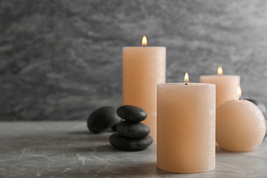 Photo of Burning candles and spa stones on table. Space for text