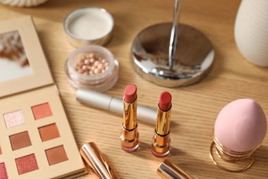 Different makeup products on wooden dressing table