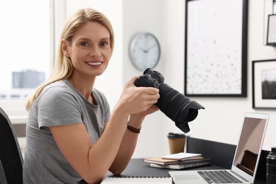 Photo of Professional photographer with digital camera at table in office