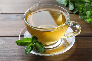 Photo of Cup of aromatic green tea with fresh mint on wooden table