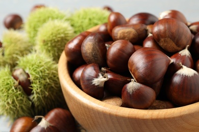 Fresh sweet edible chestnuts in wooden bowl, closeup