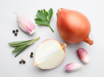 Flat lay composition with onions and spices on light background