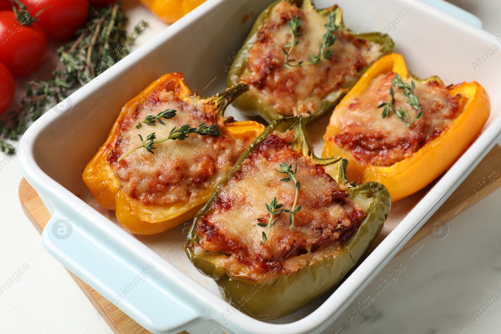 Photo of Tasty stuffed peppers in dish on white table, closeup