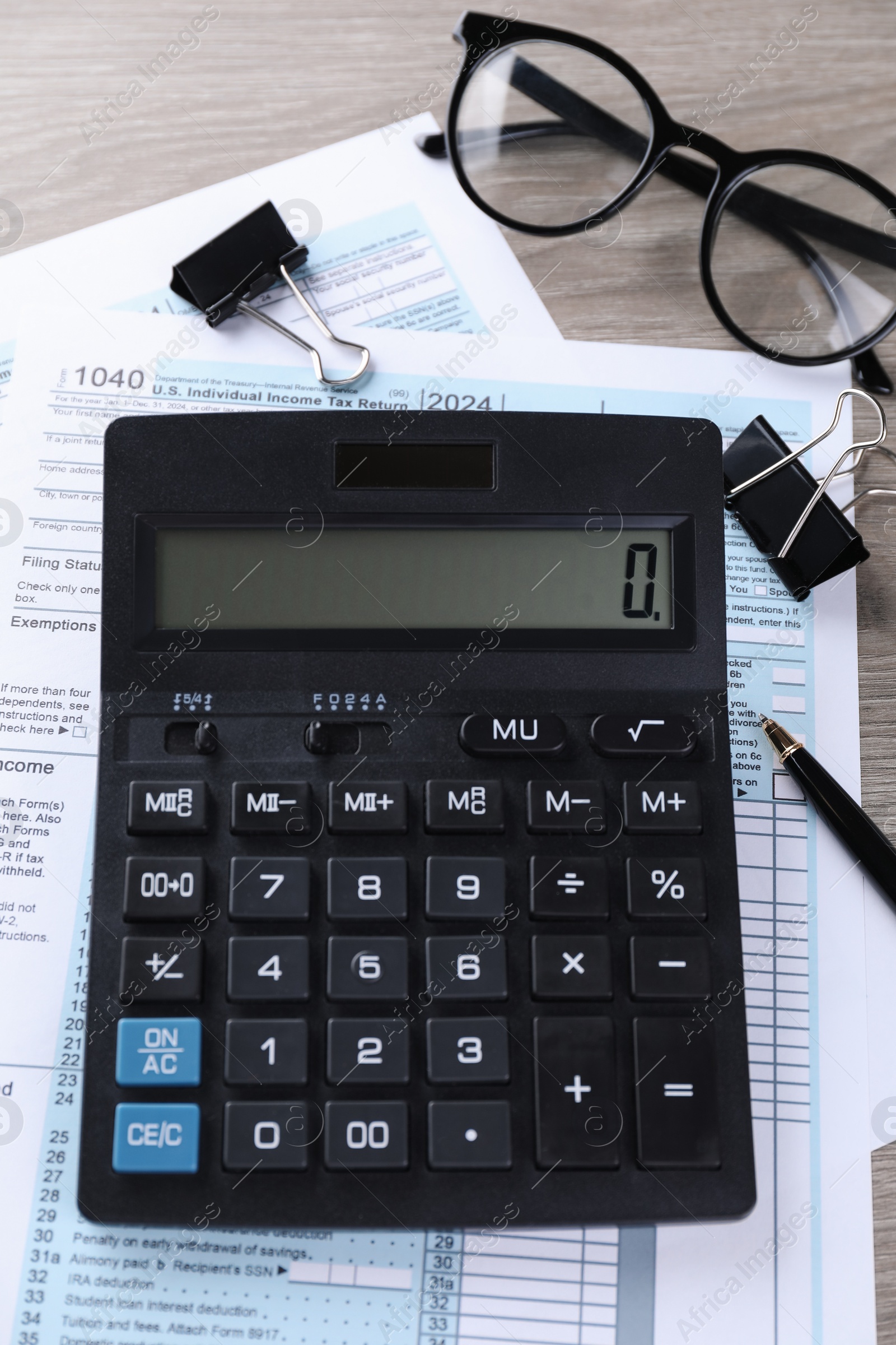 Photo of Tax accounting. Calculator, documents, glasses and stationery on wooden table, flat lay