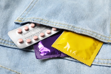 Photo of Condoms and birth control pills in pocket of jeans, closeup. Safe sex concept