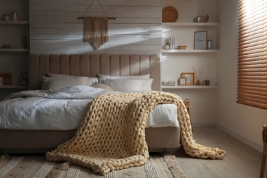 Soft chunky knit blanket on bed in stylish room