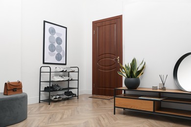 Photo of Shelving unit with shoes near white wall in hall