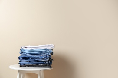 Photo of Stack of different jeans on table against color background