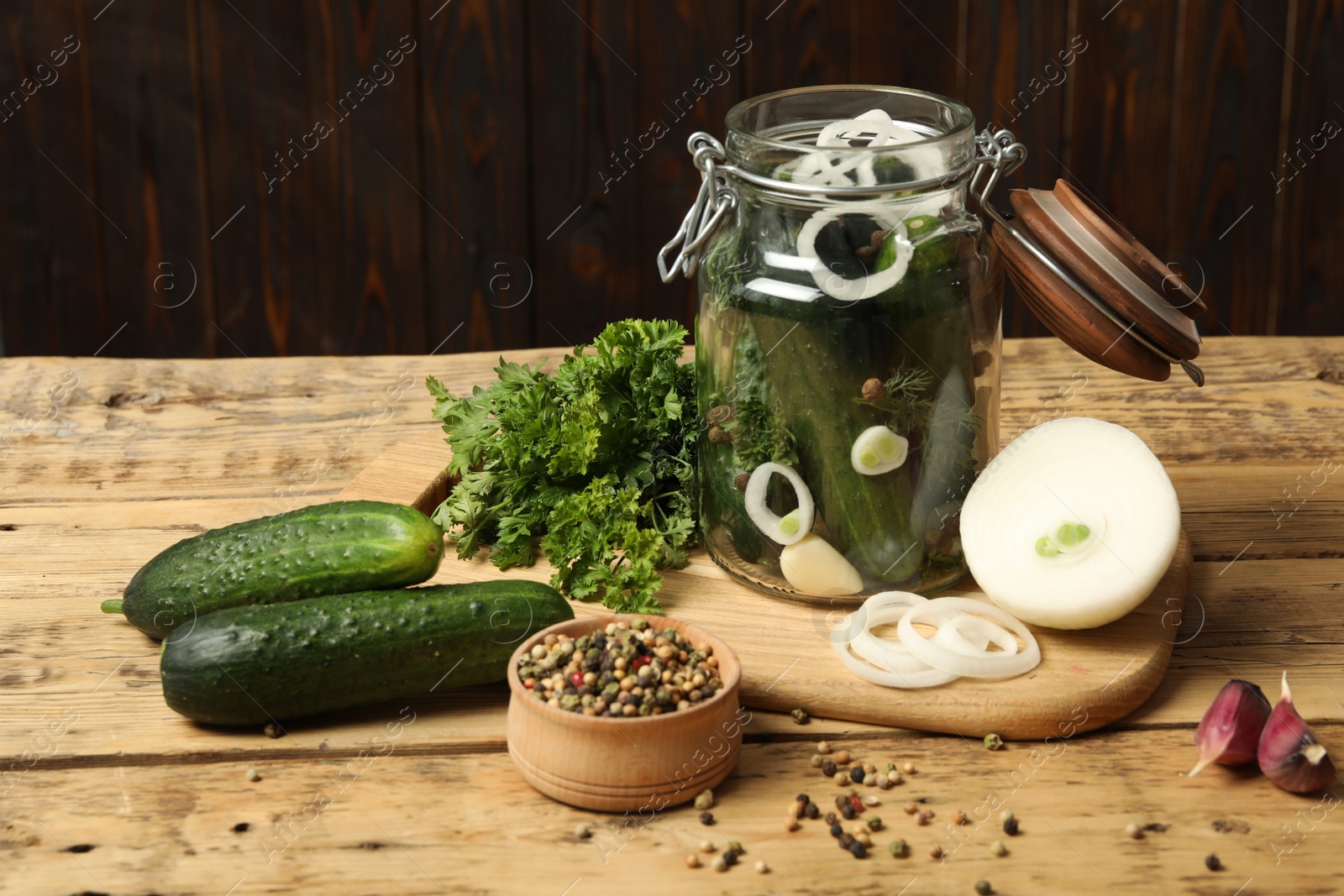 Photo of Pickling jar with fresh ripe cucumbers and spices on wooden table