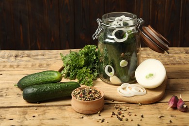 Pickling jar with fresh ripe cucumbers and spices on wooden table