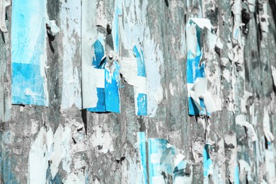 Photo of Old wall with flaky paint and torn advertisements as background, closeup