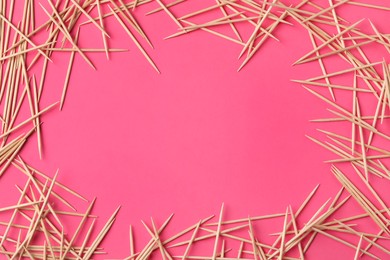 Frame of wooden toothpicks on pink background, flat lay. Space for text