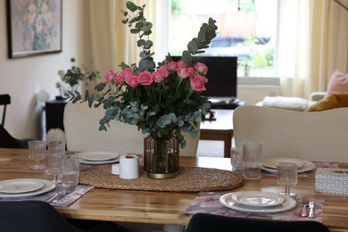 Photo of Beautiful table setting with bouquet of roses, napkins and candles in room