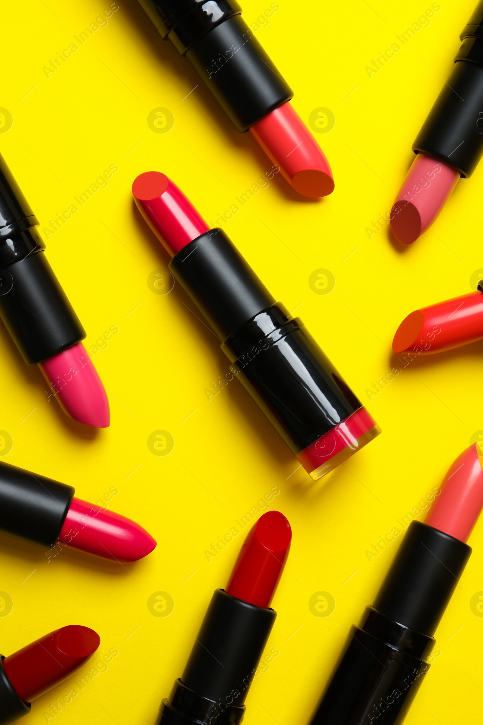 Photo of Many bright lipsticks on yellow background, flat lay