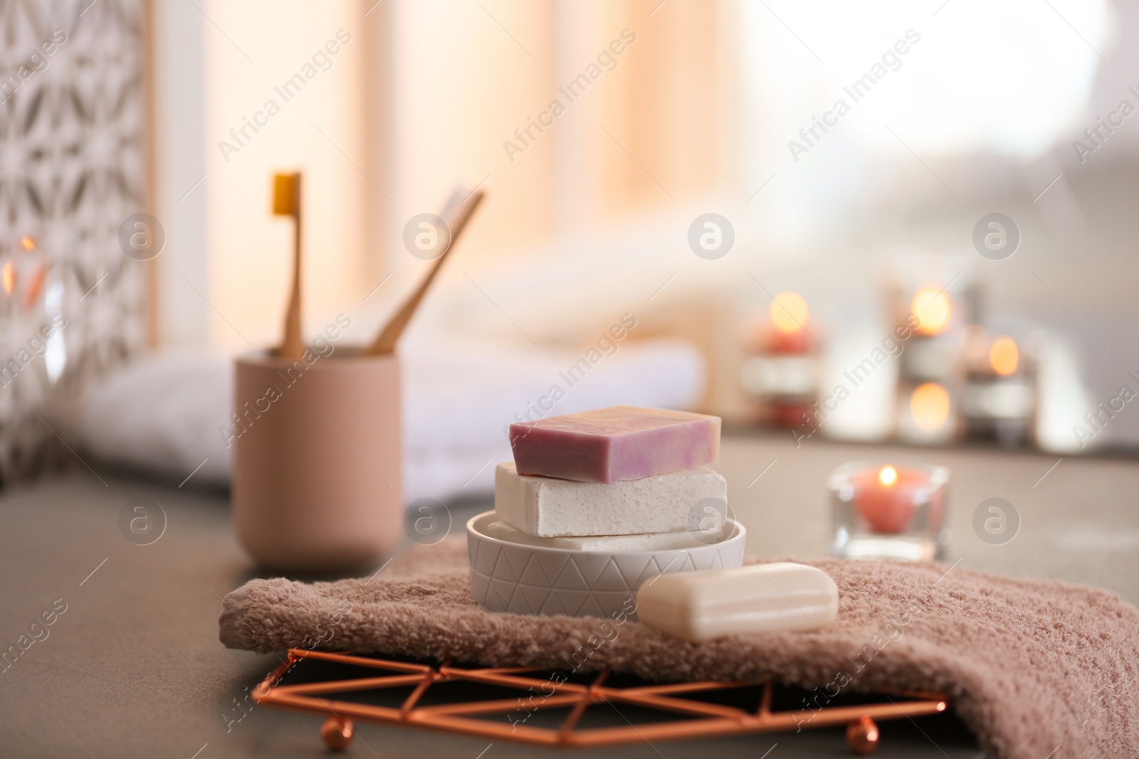 Photo of Soap bars and towel on table against blurred background. Space for text