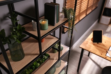 Photo of Shelving with different decor, books and houseplants near gray wall in room. Interior design